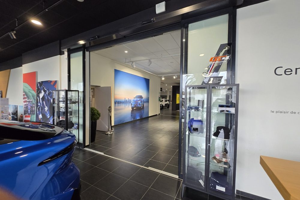 Porte coulissante automatique ouverte à l'intérieur d'une concession automobile, vue depuis le showroom