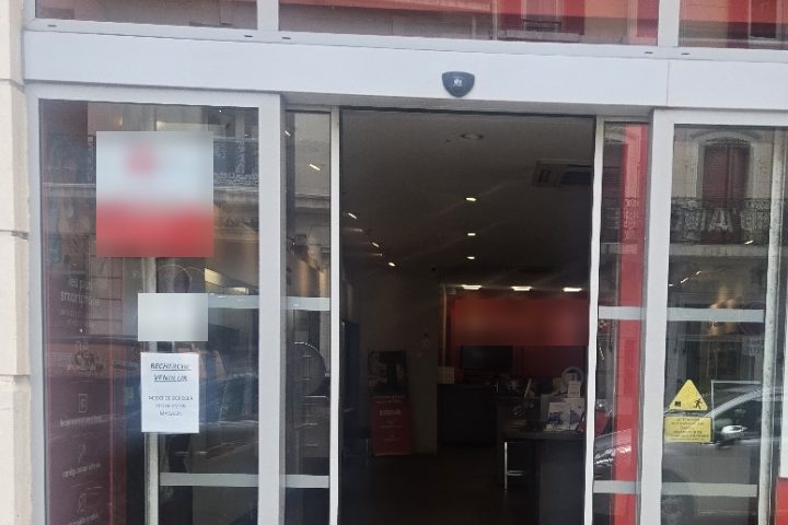 Porte automatique coulissante d'un commerce restée bloquée en position ouverte, les deux vantaux écartés, vue depuis le trottoir