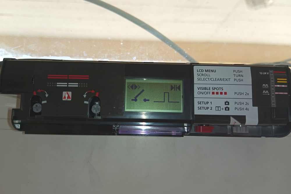 Radar de porte automatique ouvert sur son support, afficheur LCD de réglage, vis d'inclinaison et bornier 12-24 V visibles
